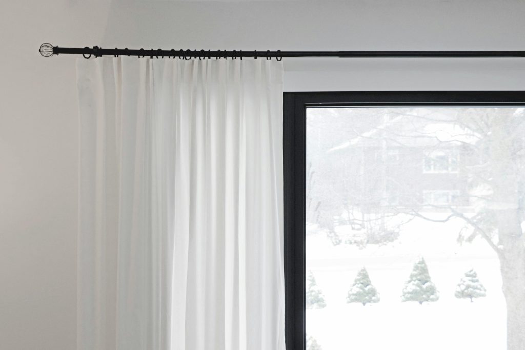White curtains partially covering a window with a snowy outdoor view. Minimalist home decor.